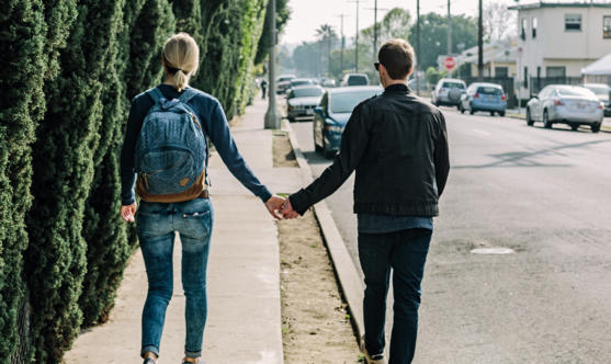 Couple holding hands as they walk on the side walk in an up-and-coming neighborhood.
